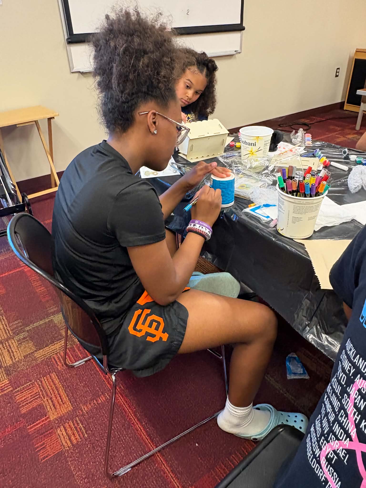 A participant painting at a craft table during a Rising Up Now art workshop.