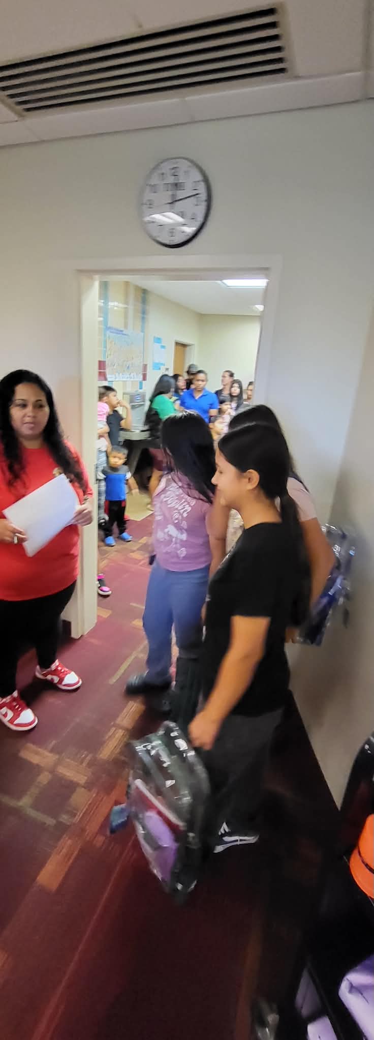 Students and families wait in line with backpacks during a Back to School event.