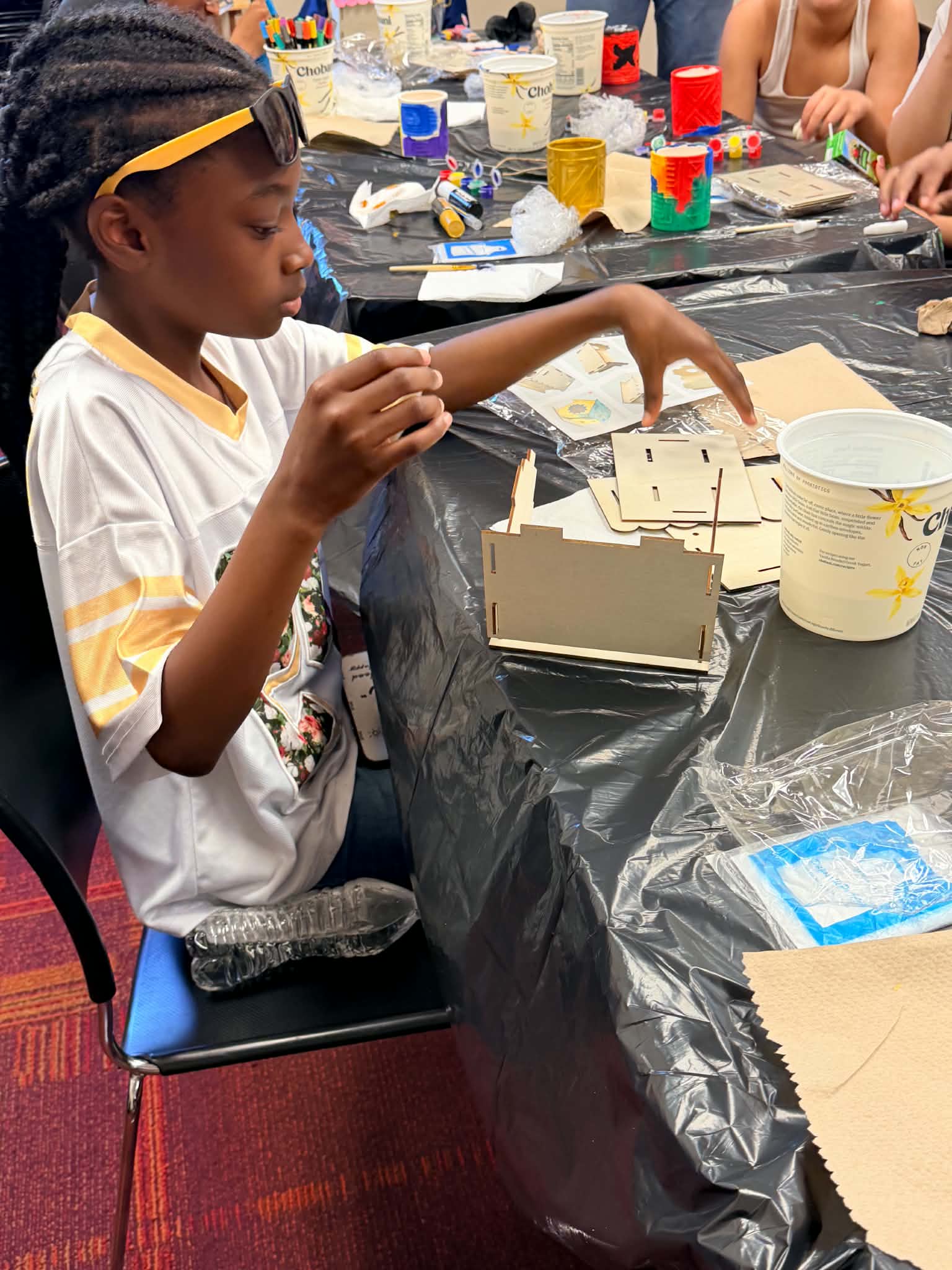 A participant painting a wood-panel project during a Rising Up Now art workshop.
