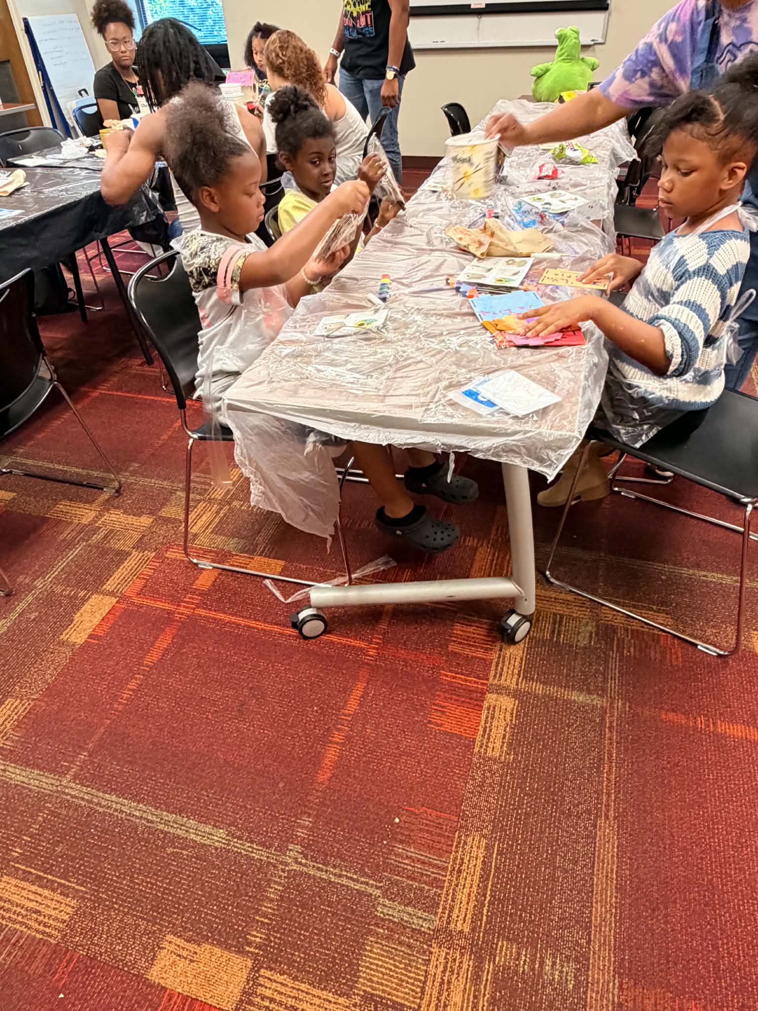 Participants seated around a craft table during a Rising Up Now art workshop.