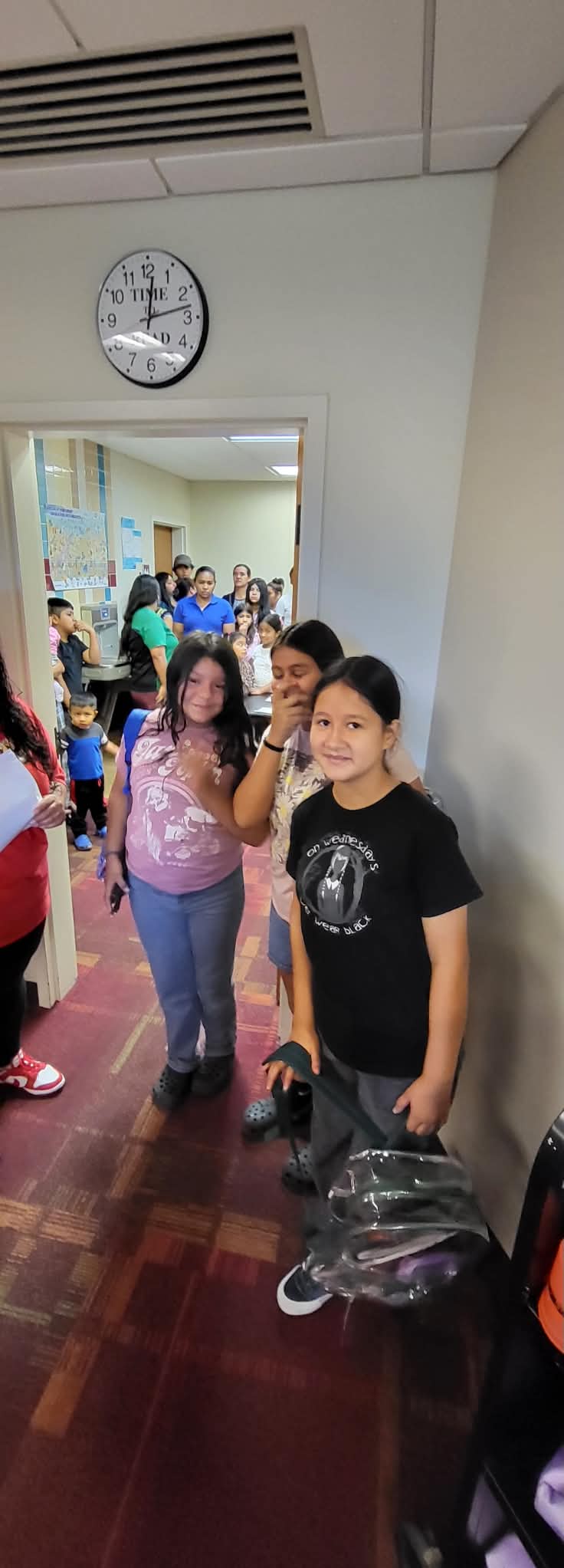 Students smile while carrying backpacks during a Back to School distribution event.